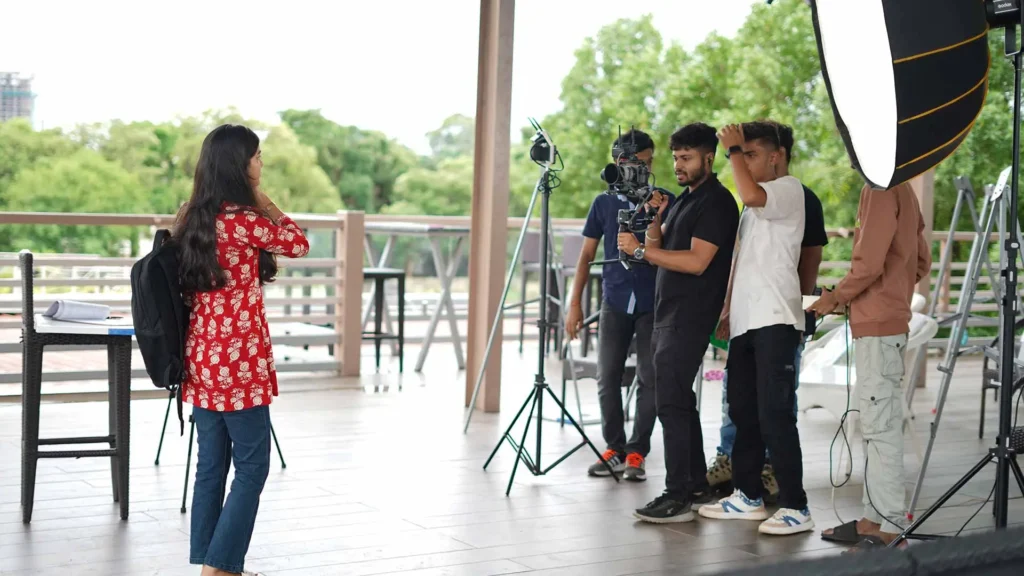 Behind-the-scenes filmmaking workshop with a camera crew filming a female actor on location.